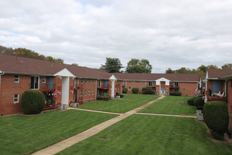 A grassy area in front of a building with a red roof.