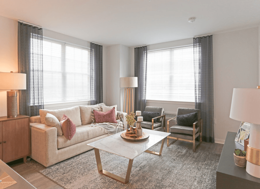 A well-lit living room with a sofa, armchairs, and a coffee table.