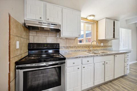 a kitchen with white cabinets and a stove and a sink