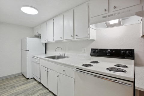 A white kitchen with a black stove top oven.