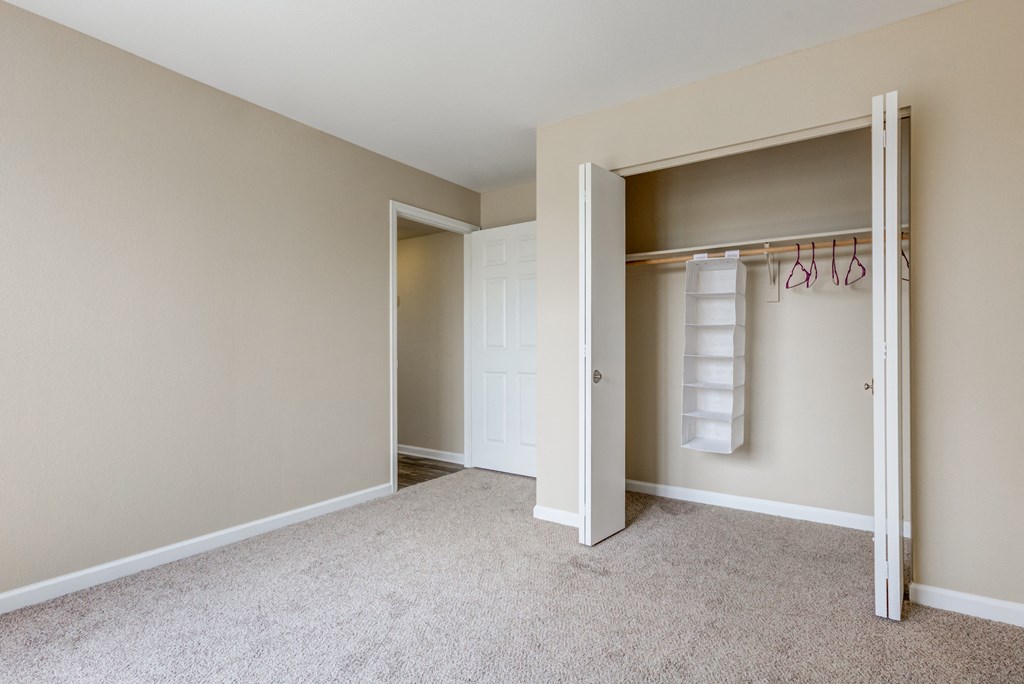 an empty bedroom with a closet and a white closet door