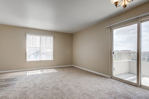 Living room with sliding glass doors to a balcony at Belle Creek Apartments, Henderson, CO