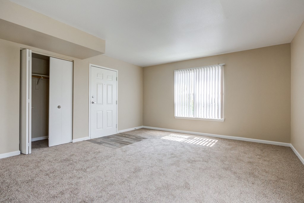 an empty living room with a closet and a window