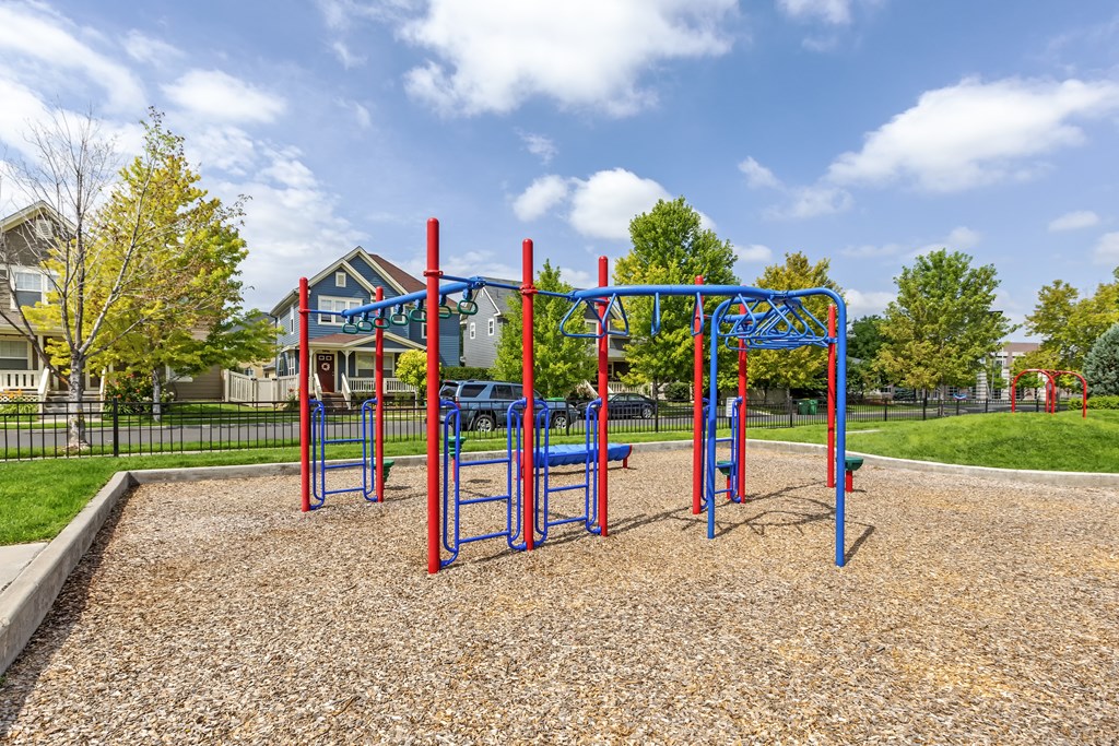 an empty playground in a park with houses in the background