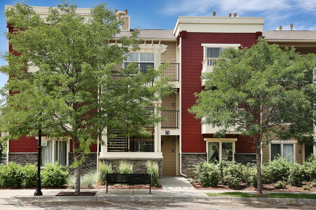 a red brick apartment building with a bench in front of it