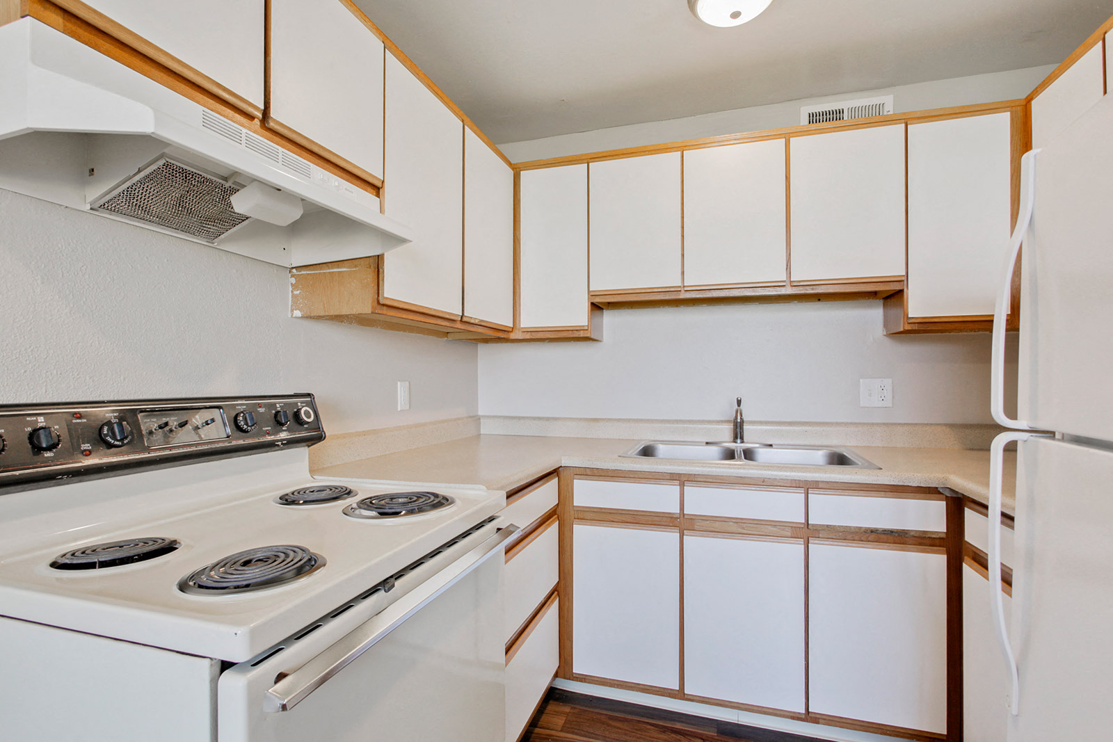 A white stove and sink in a kitchen with wooden cabinets.