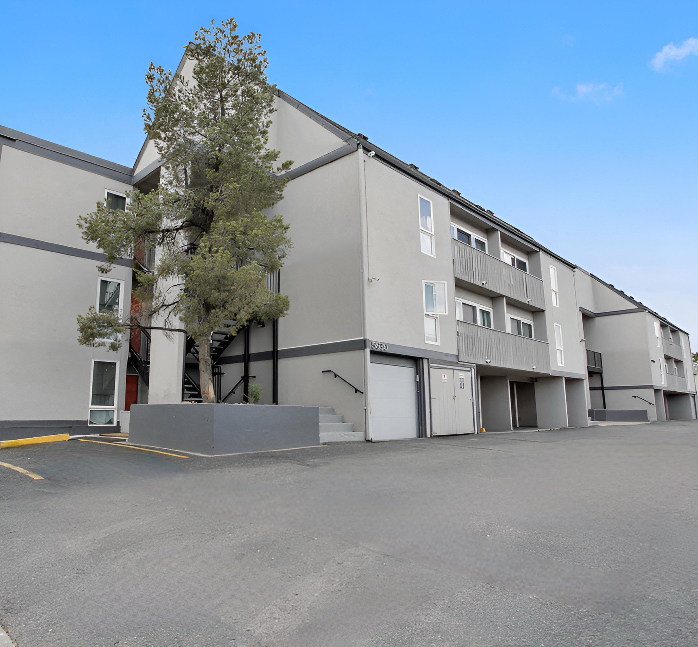 A large grey building with a tree in front of it.