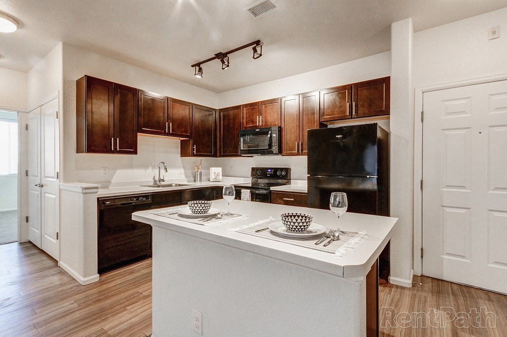 a kitchen with dark wood cabinets and white countertops