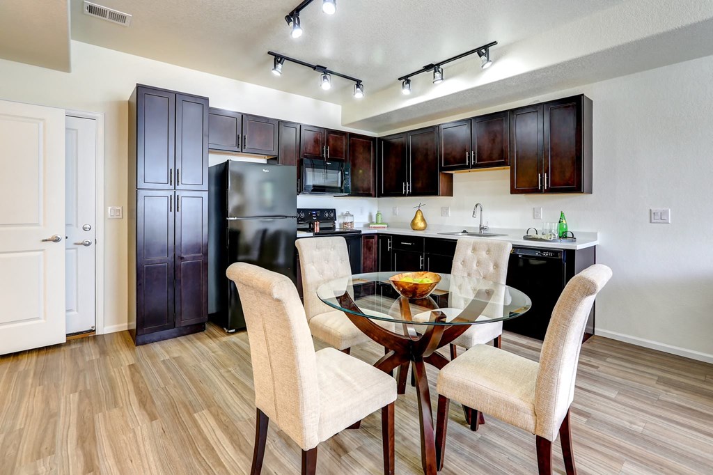 a kitchen with dark wood cabinets and a glass table with four chairs