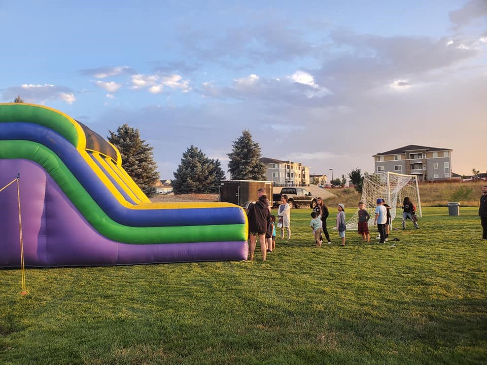 a group of children playing in a field with a large inflatable slide