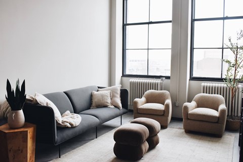A living room with a grey couch, two armchairs, a coffee table, and a plant.