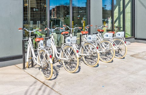 A row of bicycles are parked in front of a building.