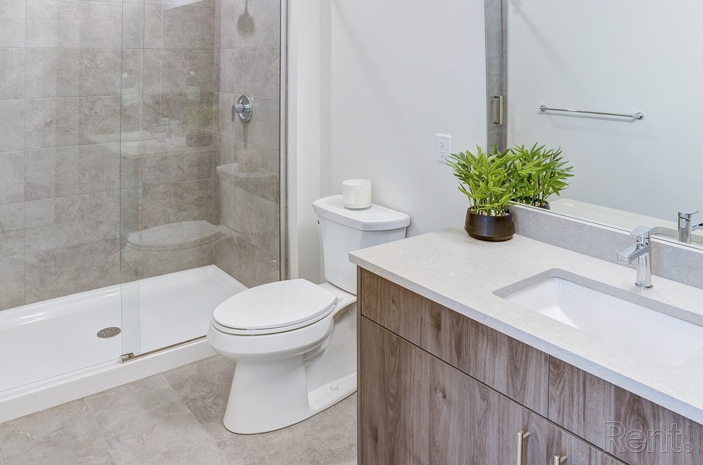 A white toilet sits next to a walk-in shower in a bathroom at The Anthem at Square 10 Apartments, Connecticut