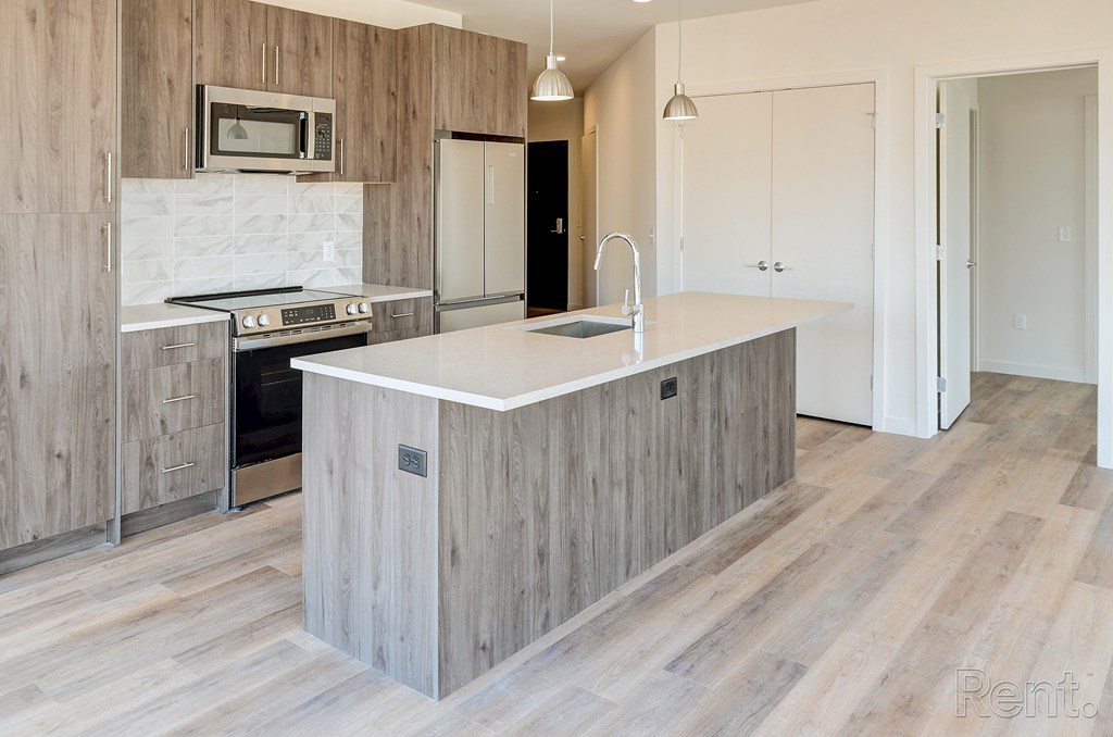 A kitchen with a white countertop and wooden cabinets at The Anthem at Square 10 Apartments, New Haven, Connecticut