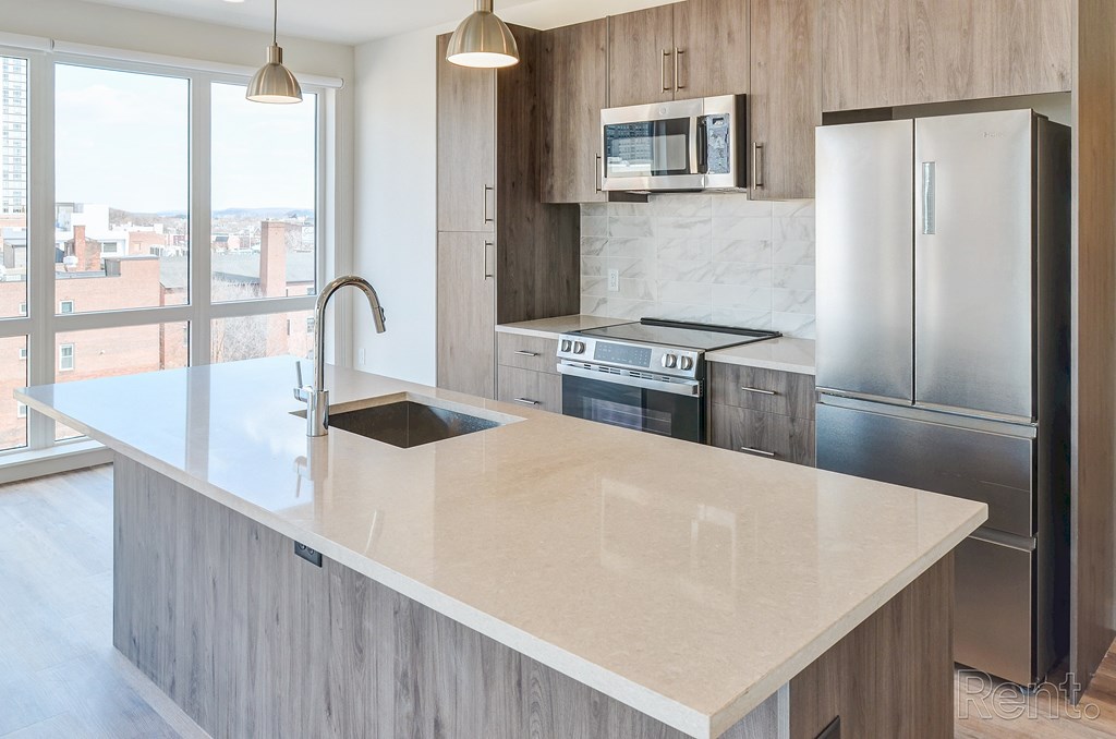 A modern kitchen with a marble countertop and stainless steel appliances at The Anthem at Square 10 Apartments, New Haven