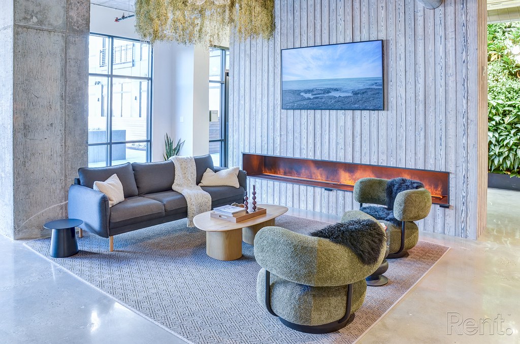 A living room with a grey couch, a green armchair and a fireplace at The Anthem at Square 10 Apartments, New Haven, Connecticut
