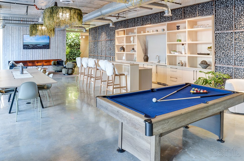 A pool table in a room with a blue cloth and white cues at The Anthem at Square 10 Apartments, New Haven