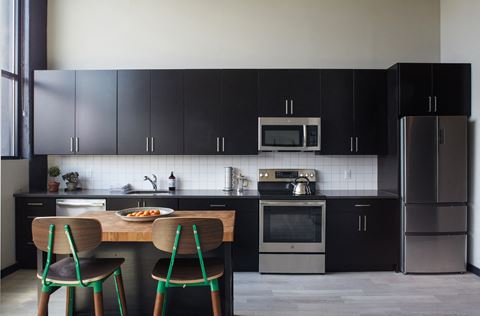 a kitchen with black cabinets and a table with three stools