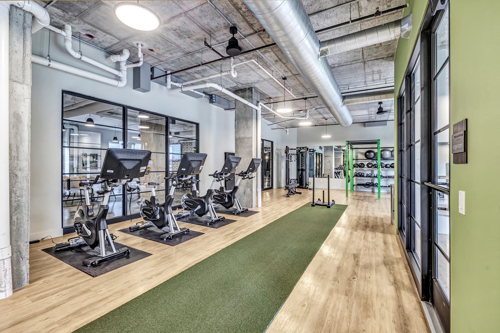 a gym with treadmills and other exercise equipment in a room with glass doors