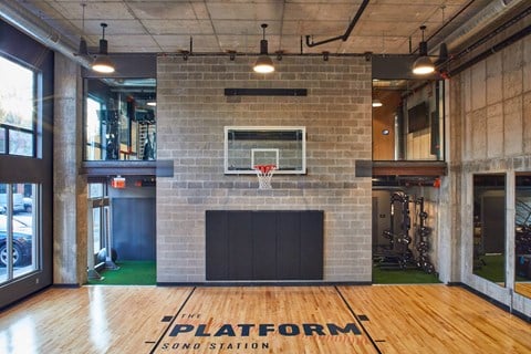 a gym with a basketball hoop and a brick wall