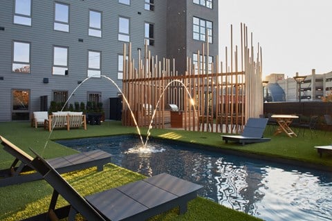 a pool with water sprinklers in front of a building