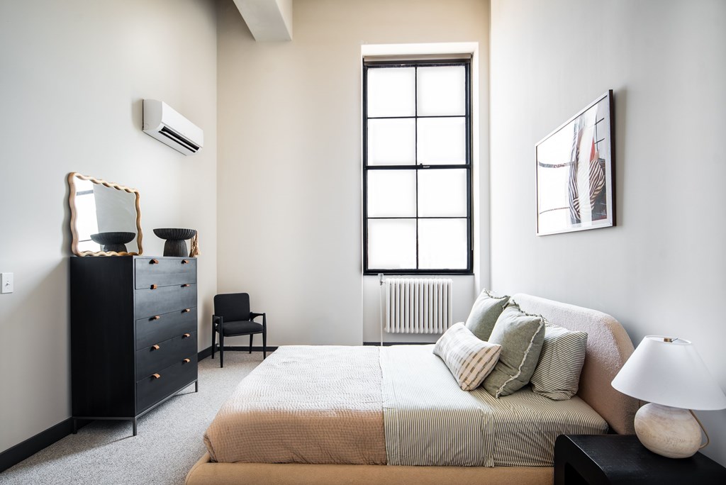 A bedroom with a bed, a dresser, a chair, and a window.