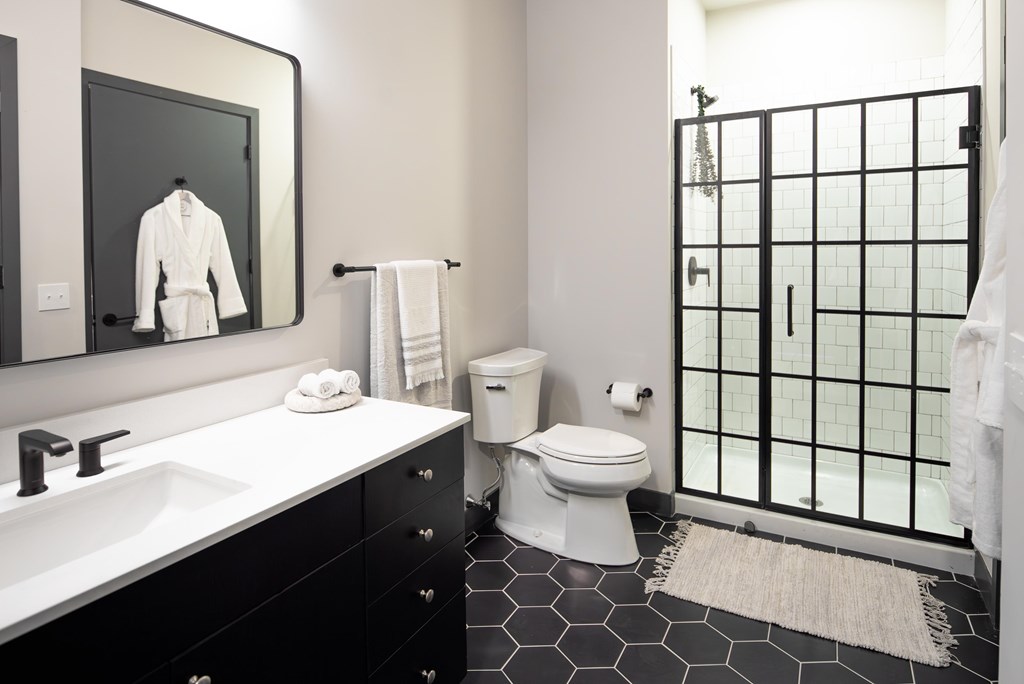 A bathroom with a white sink, toilet, and a mirror.