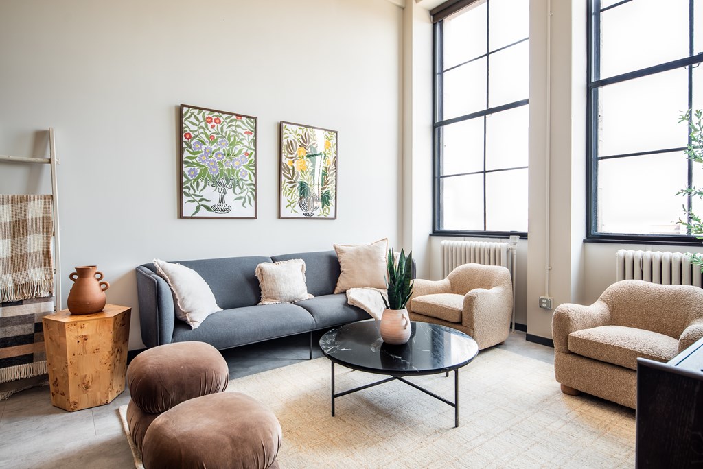 A living room with a grey couch, a coffee table, and two chairs.
