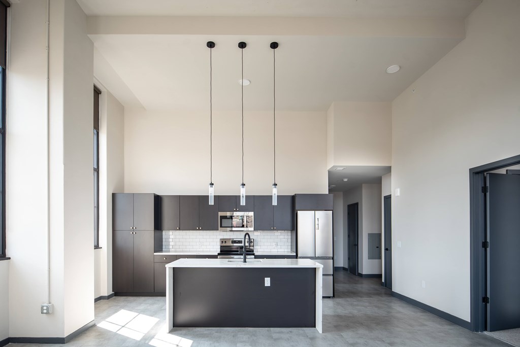 A modern kitchen with a large island and pendant lights.
