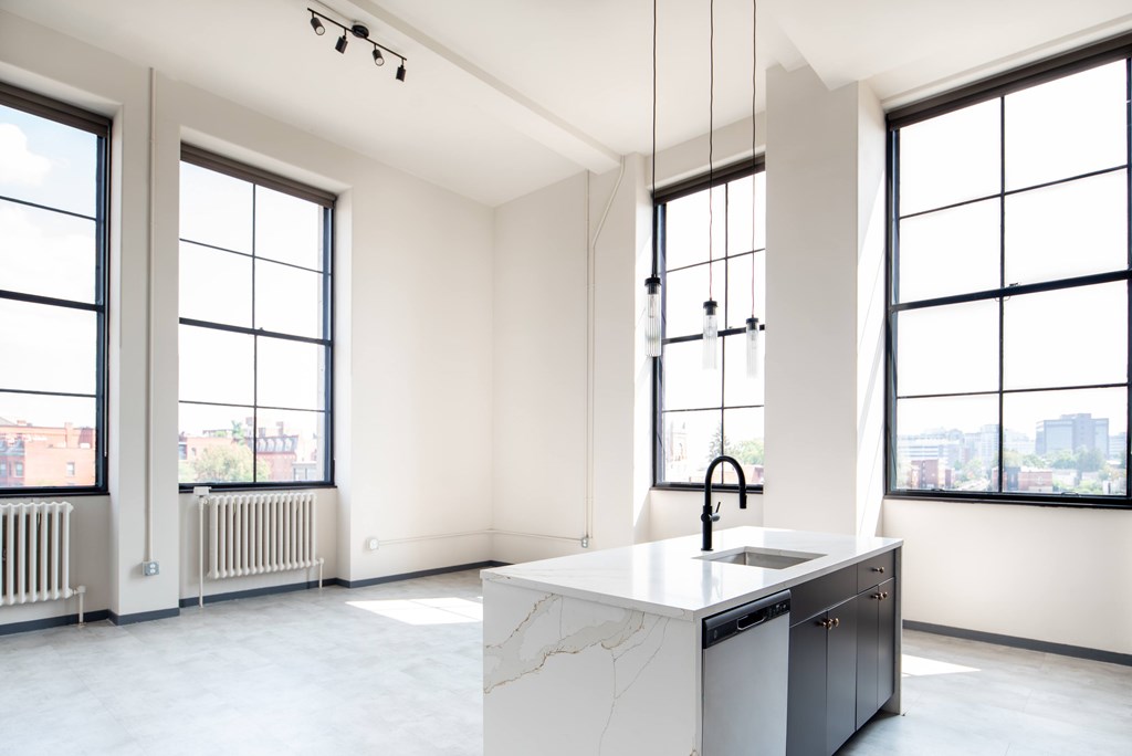 A modern kitchen with a marble countertop and large windows.