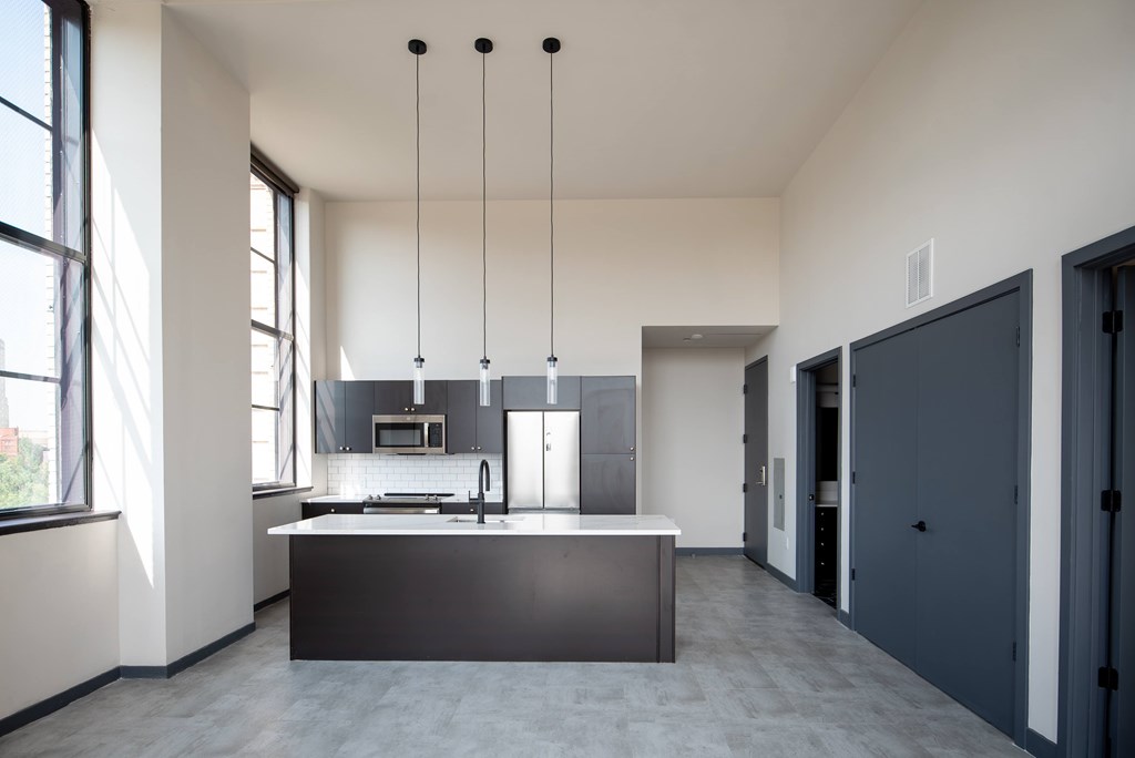 A modern kitchen with a large island and pendant lights.