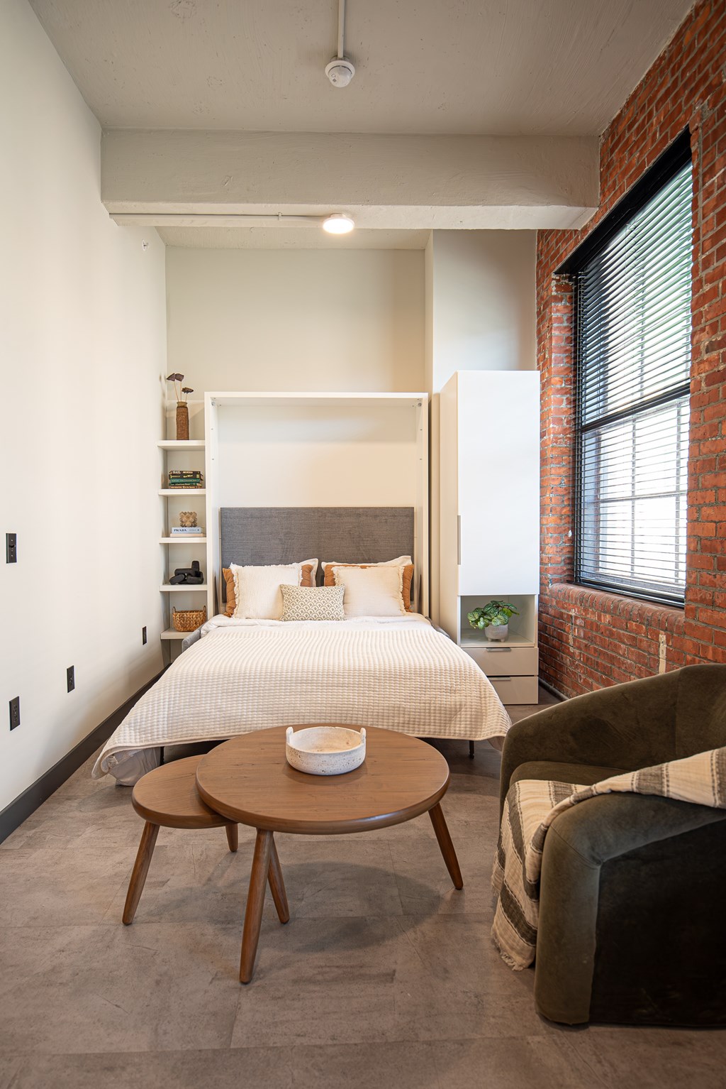 A bedroom with a bed, a chair, and a table.