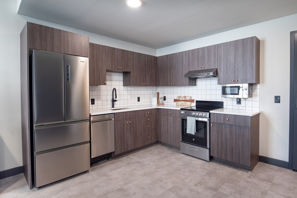 A modern kitchen with a refrigerator, oven, and microwave.