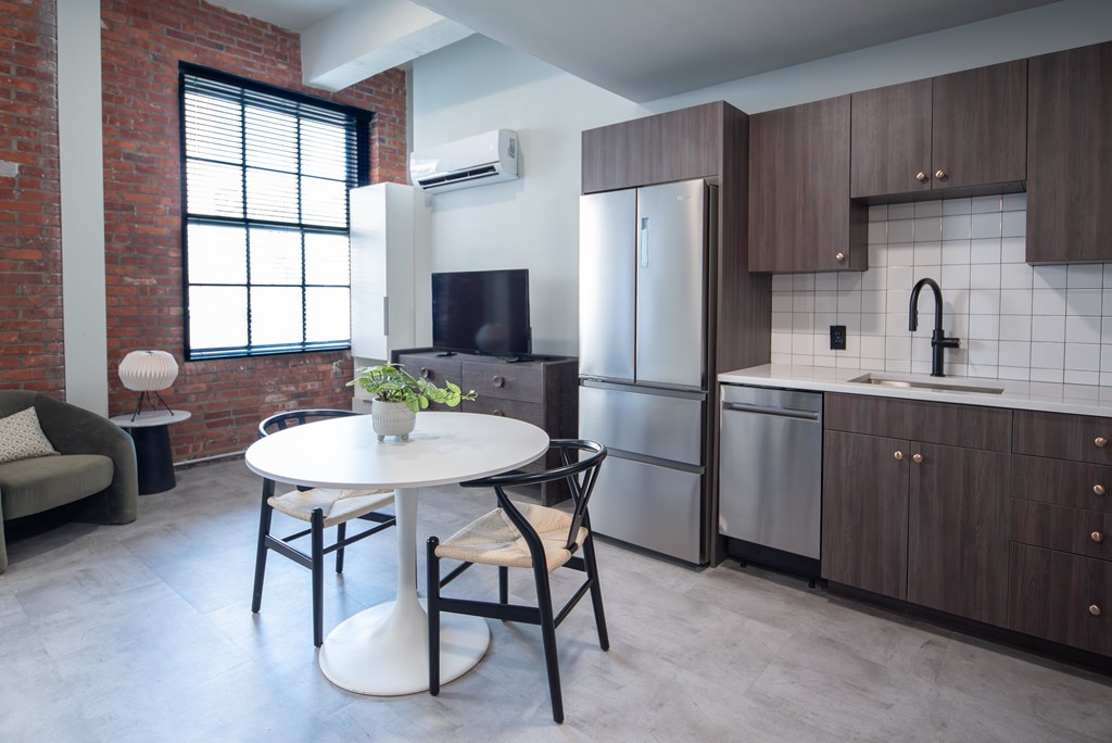 A kitchen with a table and chairs in front of a refrigerator.