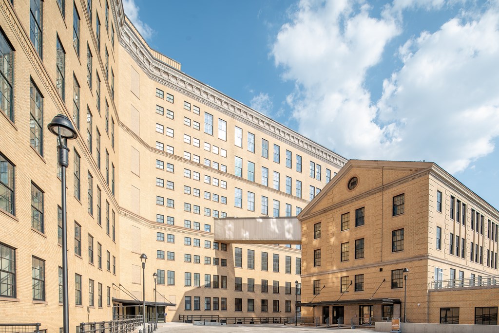 A modern building with a glass facade is situated between two older buildings.