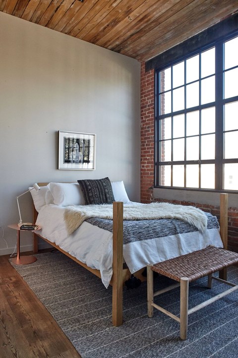 a bedroom with a bed and a rug in front of a window