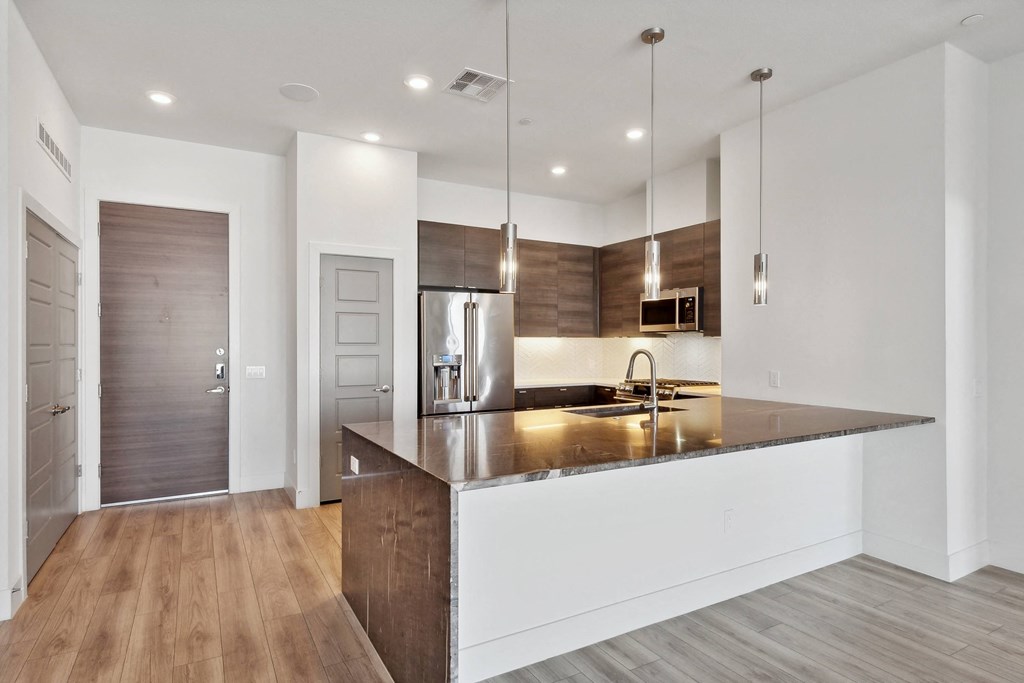 a kitchen with a large island with a sink and a refrigerator