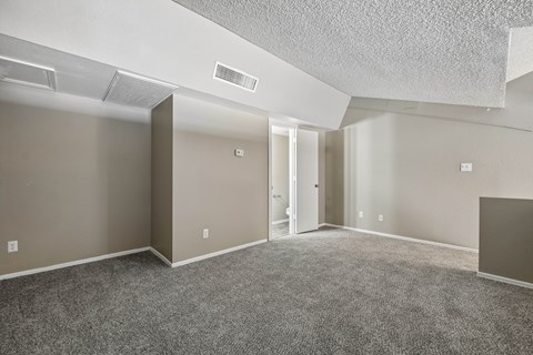 A spacious room with carpeted floor and a ceiling fan.