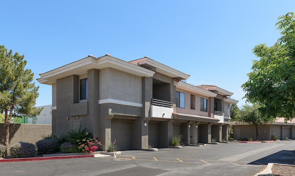 a row of houses in a parking lot with trees in the background