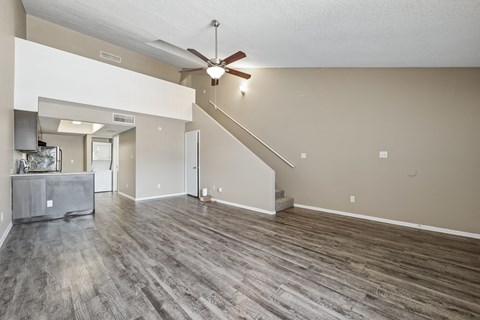 A spacious living room with a grey sofa and a wooden floor.