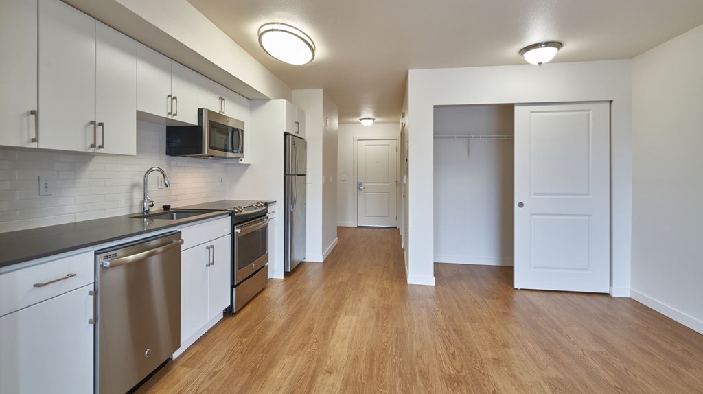 A kitchen with white cabinets and a wooden floor.