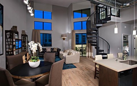 A modern living room with a spiral staircase and a dining table set for six.