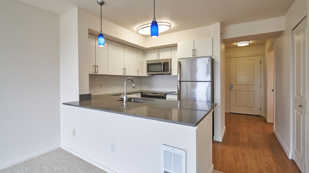 A kitchen with a stainless steel refrigerator and a microwave above the stove.