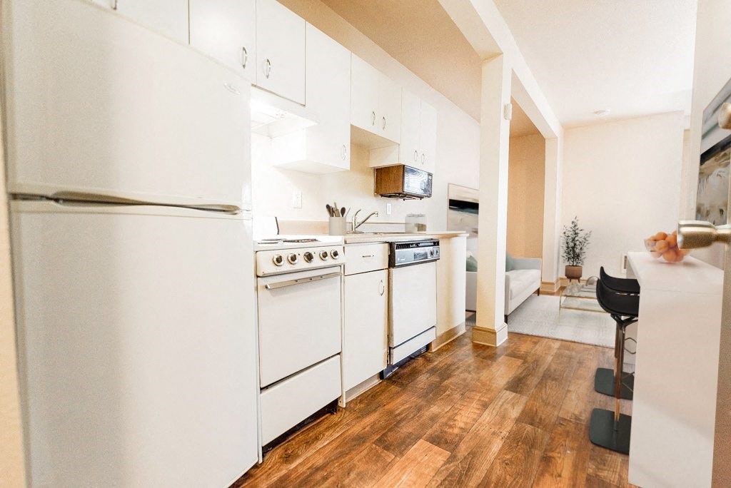 a kitchen with white appliances and a wood floor at Zindorf, Seattle, WA