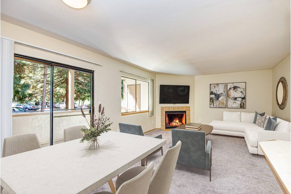 A living room with a fireplace and a dining table. at Autumn Village, Milton, WA, 98354