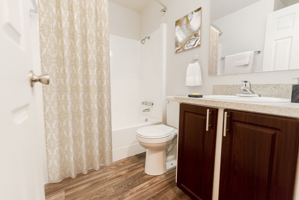 A white toilet sits in a bathroom with a white shower curtain.