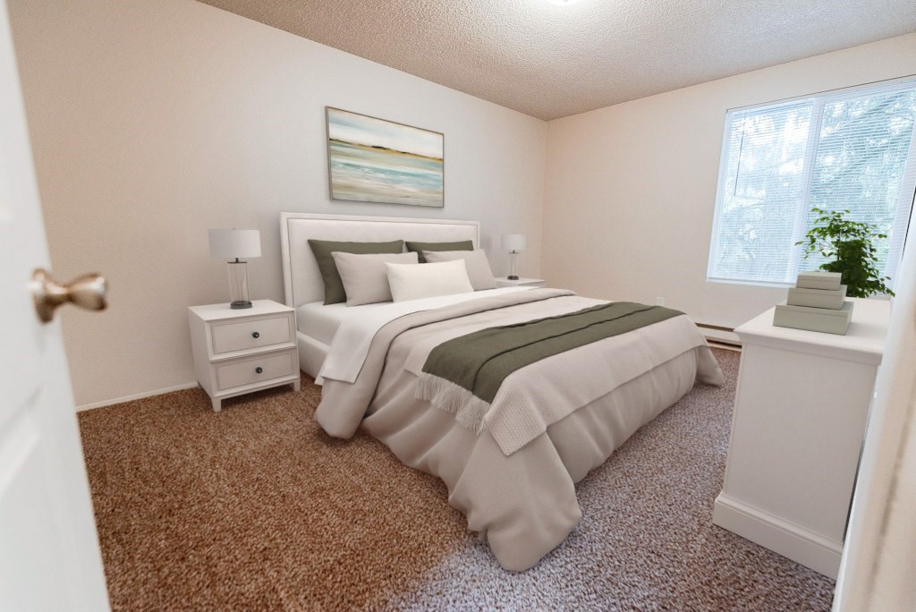 A bedroom with a large bed and a nightstand with a lamp.