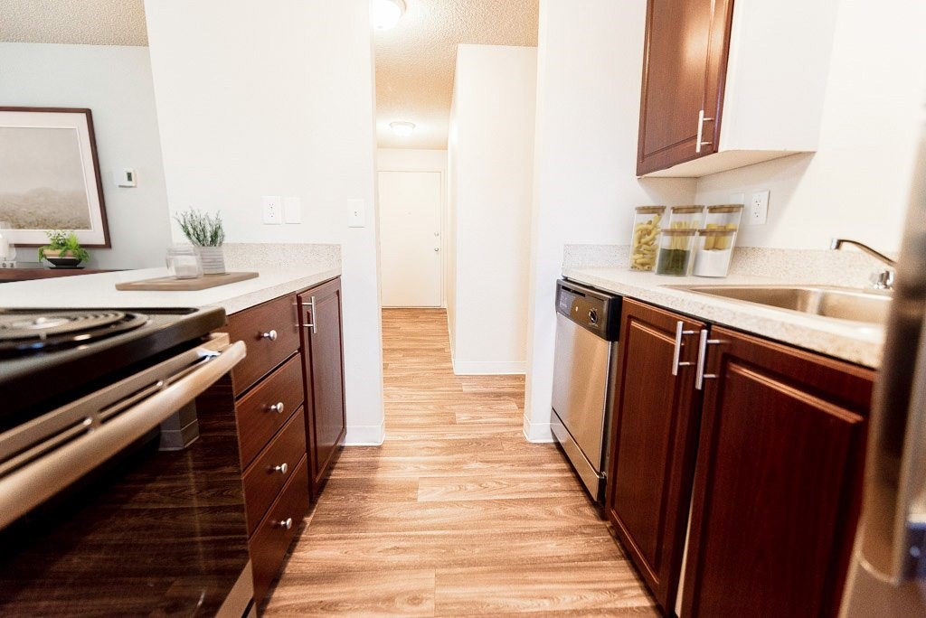 A kitchen with wooden floors and brown cabinets.
