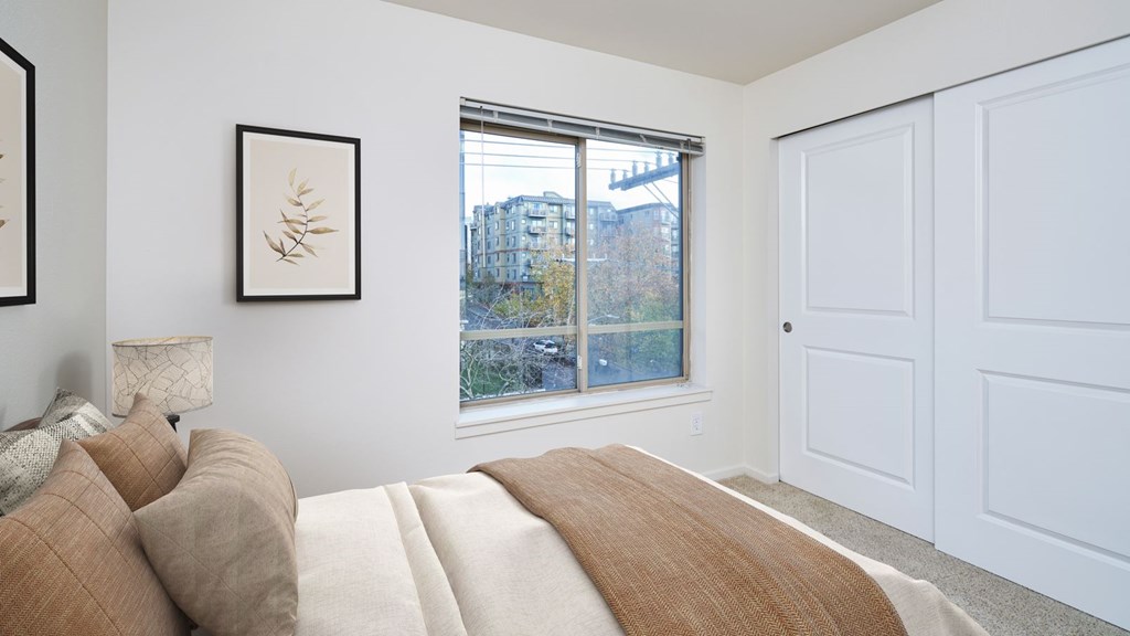 A bedroom with a large bed and a window overlooking a cityscape.
