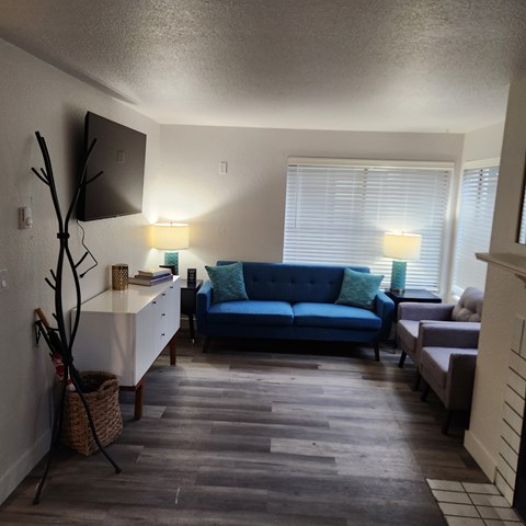 A living room with a blue couch and a wooden floor.